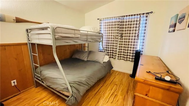 bedroom with wood-type flooring and vaulted ceiling