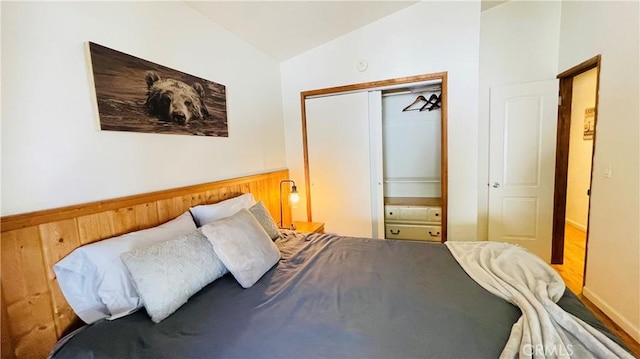 bedroom with hardwood / wood-style floors, vaulted ceiling, and a closet