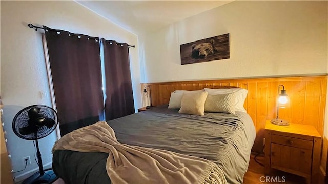 bedroom with vaulted ceiling and wooden walls