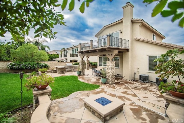 rear view of property with a yard, an outdoor fire pit, a balcony, cooling unit, and a patio area