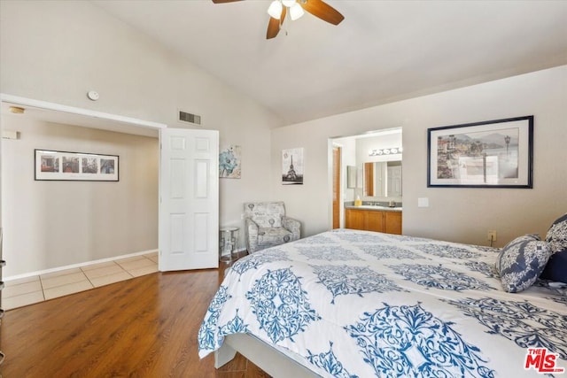 bedroom with ceiling fan, wood-type flooring, connected bathroom, and vaulted ceiling