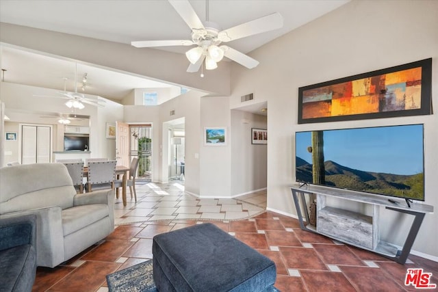 living room featuring ceiling fan, dark tile patterned floors, and high vaulted ceiling