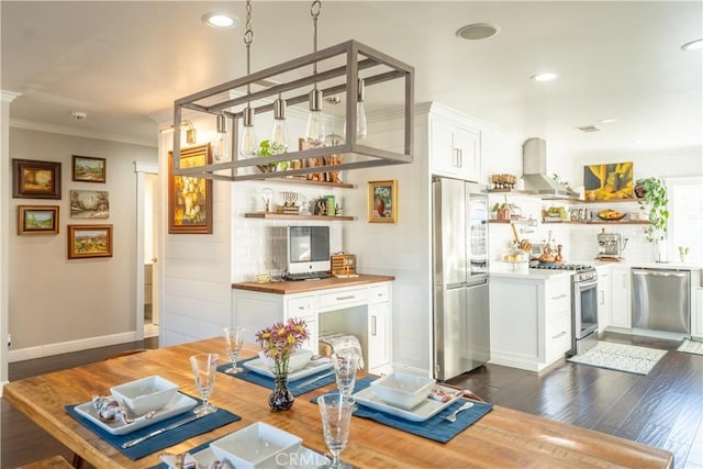 bar featuring butcher block counters, stainless steel appliances, dark hardwood / wood-style floors, wall chimney exhaust hood, and white cabinets