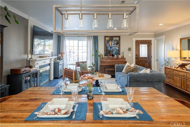 dining room with hardwood / wood-style floors, ornamental molding, and a tiled fireplace