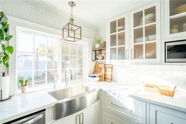 kitchen with decorative light fixtures, decorative backsplash, stainless steel appliances, and ornamental molding