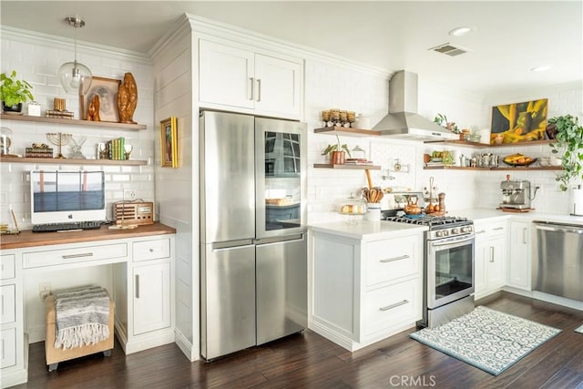 kitchen with stainless steel appliances, backsplash, white cabinets, and wall chimney range hood