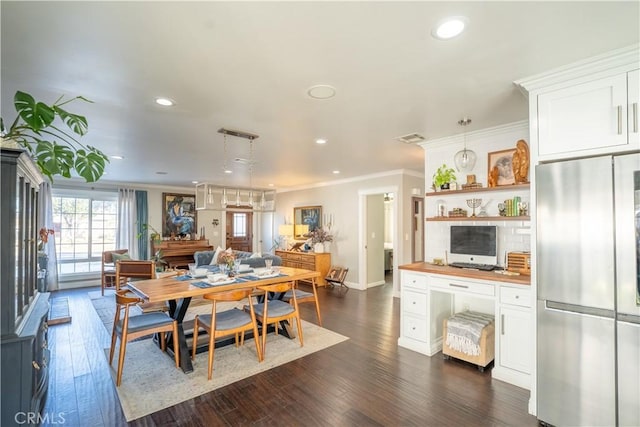 dining area featuring dark wood-type flooring and crown molding