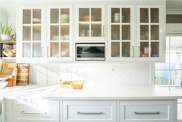 bar featuring white cabinetry, ornamental molding, tasteful backsplash, and light stone countertops