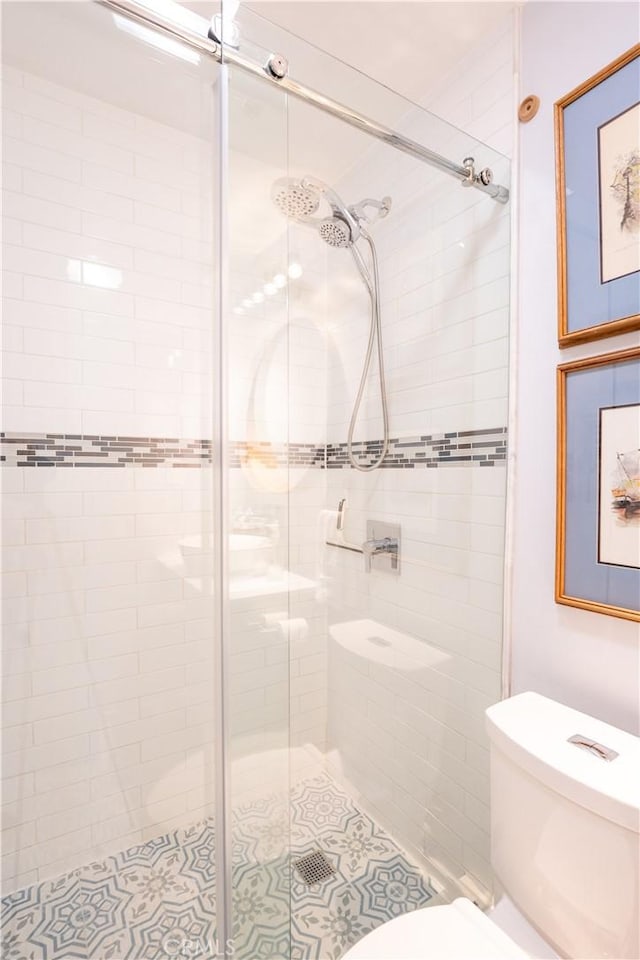 bathroom featuring a shower with shower door and toilet