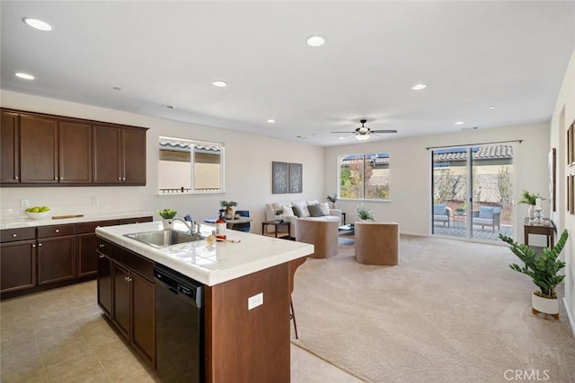 kitchen featuring light carpet, a breakfast bar, a kitchen island with sink, sink, and dishwasher