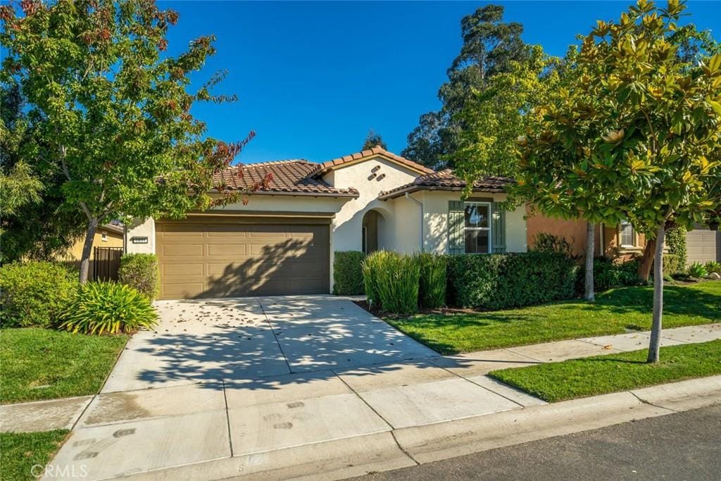 mediterranean / spanish-style home featuring a garage and a front lawn