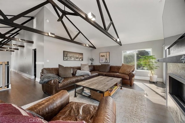 living room featuring high vaulted ceiling, a tile fireplace, hardwood / wood-style floors, and beamed ceiling