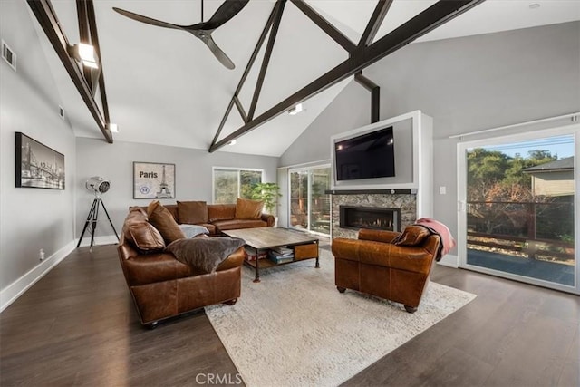 living room with dark wood-type flooring, ceiling fan, a fireplace, and high vaulted ceiling