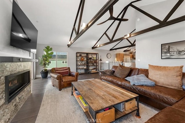 living room featuring dark wood-type flooring, ceiling fan, a fireplace, and lofted ceiling with beams