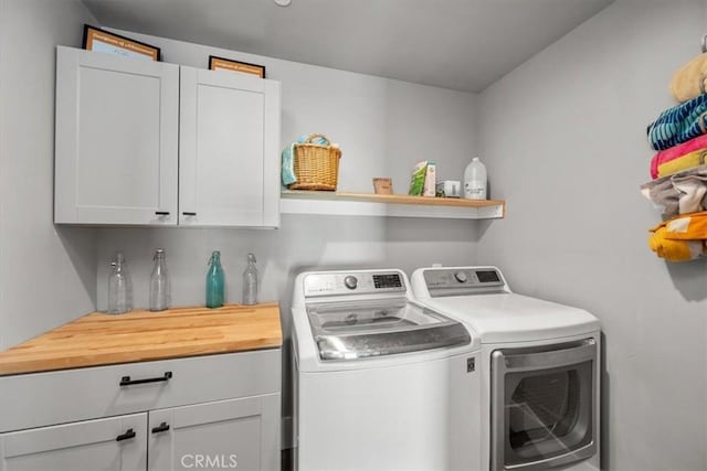 clothes washing area with cabinets and washer and dryer