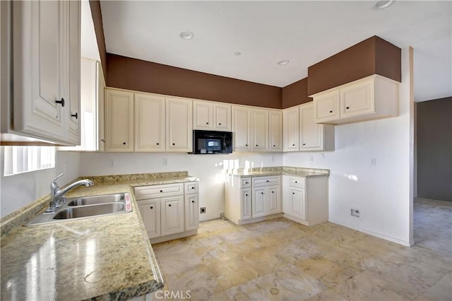 kitchen with light stone countertops, white cabinetry, and sink