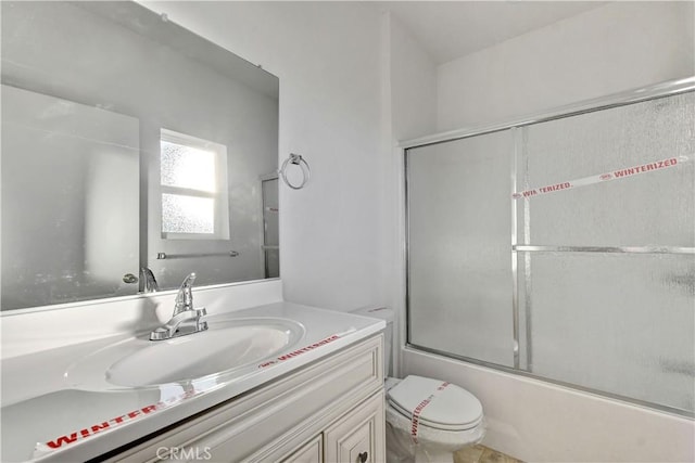 full bathroom featuring combined bath / shower with glass door, vanity, and toilet