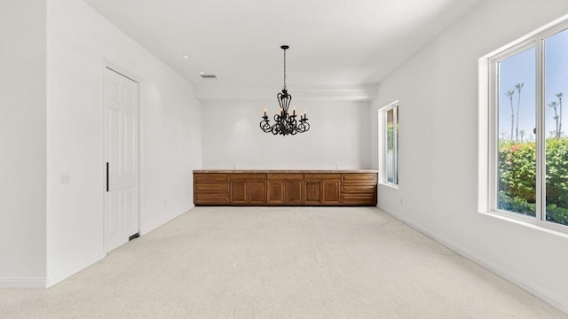 empty room featuring light carpet and an inviting chandelier