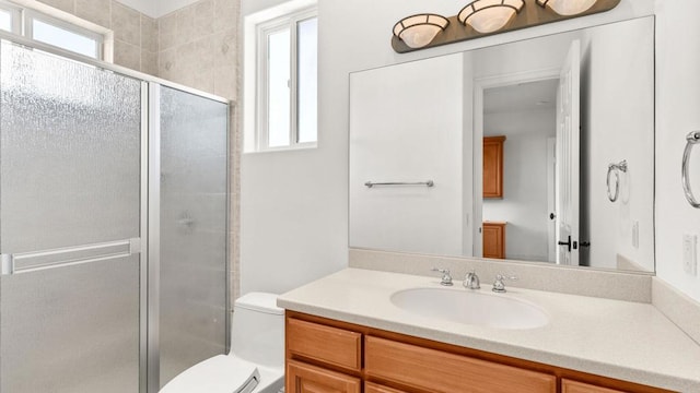 bathroom featuring vanity, a shower with shower door, and toilet