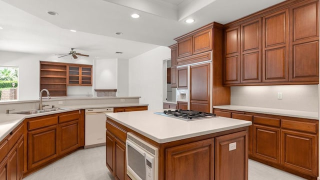 kitchen featuring sink, built in appliances, ceiling fan, a kitchen island, and kitchen peninsula