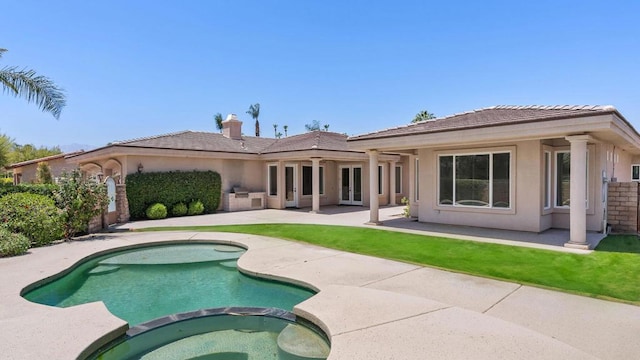 rear view of house with a swimming pool with hot tub and a patio