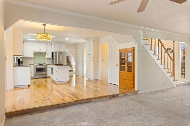 kitchen featuring pendant lighting, white cabinetry, stainless steel appliances, and light hardwood / wood-style flooring