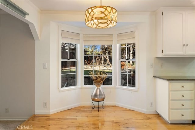 dining room with light wood-type flooring and ornamental molding