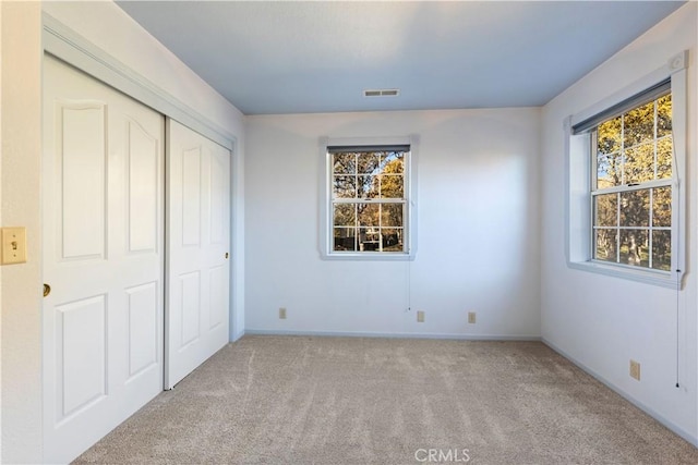 unfurnished bedroom with light carpet and a closet