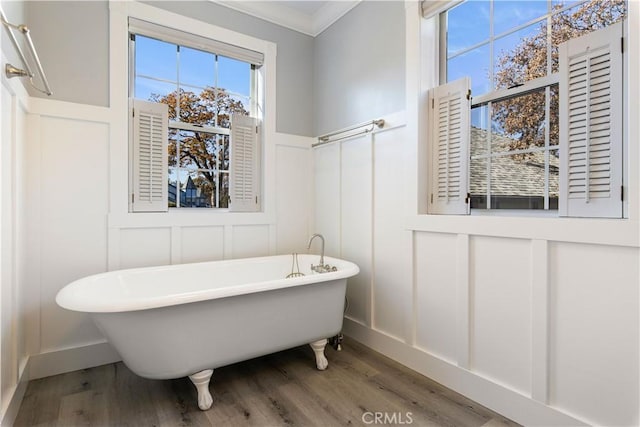 bathroom with wood-type flooring, a bath, and ornamental molding