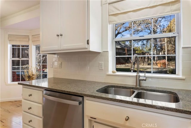 kitchen with sink, stainless steel dishwasher, dark stone countertops, light hardwood / wood-style floors, and white cabinets