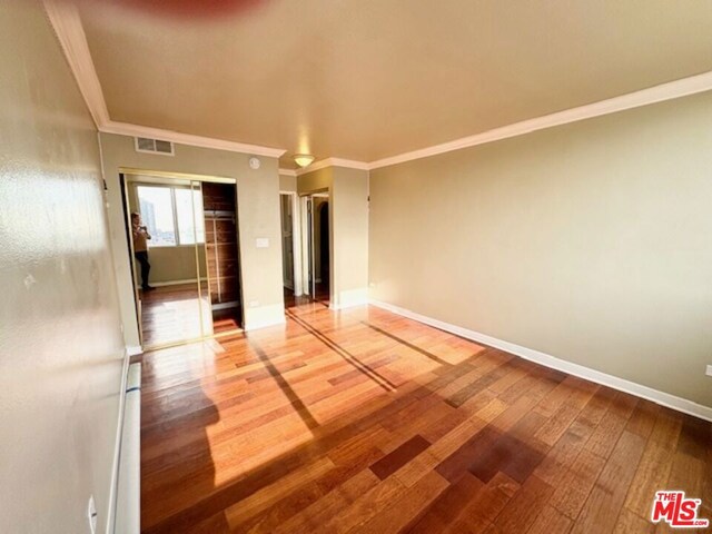 unfurnished room with ornamental molding and hardwood / wood-style floors