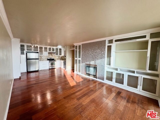 unfurnished living room with built in shelves, dark hardwood / wood-style flooring, ornamental molding, and a fireplace