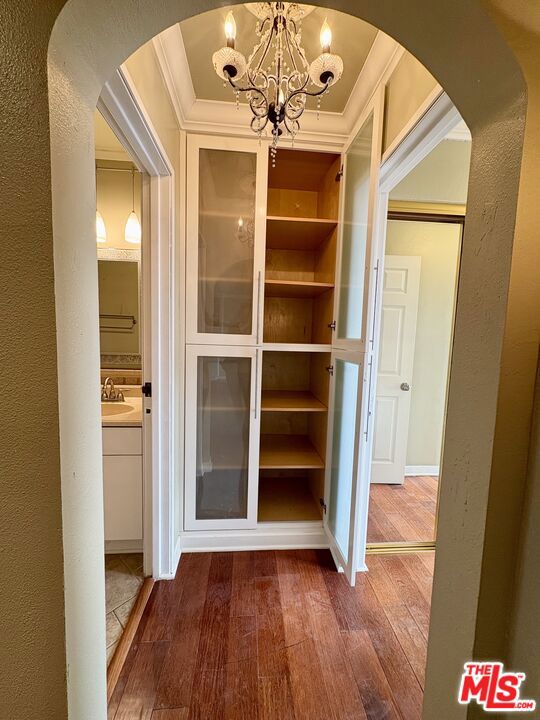 interior space with dark wood-type flooring, a notable chandelier, sink, and crown molding