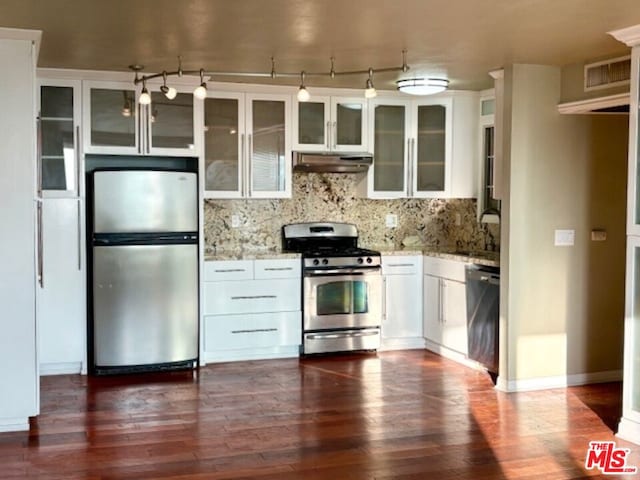 kitchen featuring appliances with stainless steel finishes, decorative backsplash, dark hardwood / wood-style flooring, white cabinets, and light stone counters