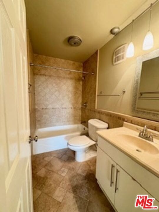 full bathroom with vanity, tiled shower / bath combo, and toilet