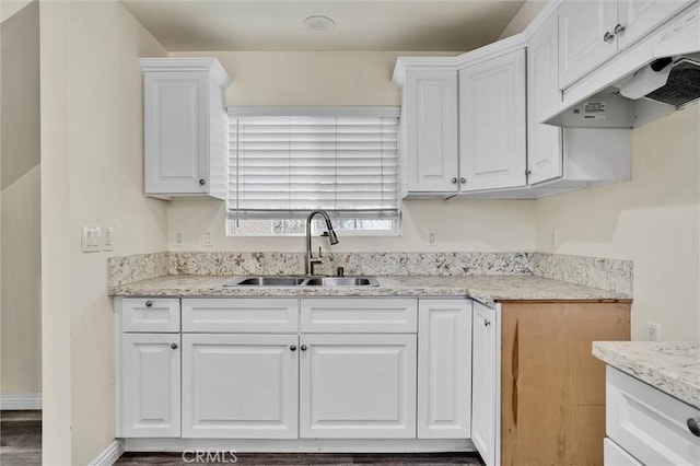 kitchen featuring dark hardwood / wood-style floors, light stone countertops, white cabinetry, and sink