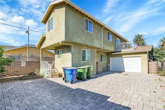 rear view of property featuring a balcony and a garage