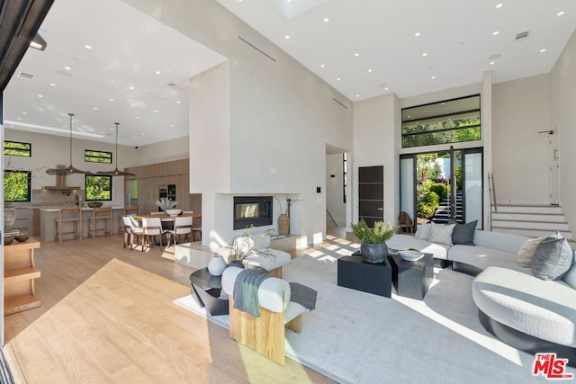 living room with light hardwood / wood-style floors, a multi sided fireplace, and a towering ceiling