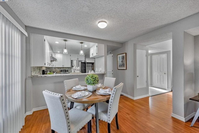 dining space featuring a textured ceiling and light wood-type flooring