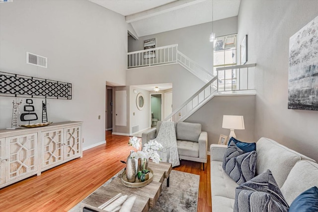 living room with beamed ceiling, hardwood / wood-style flooring, and high vaulted ceiling