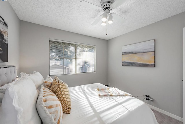 bedroom with ceiling fan, carpet floors, and a textured ceiling