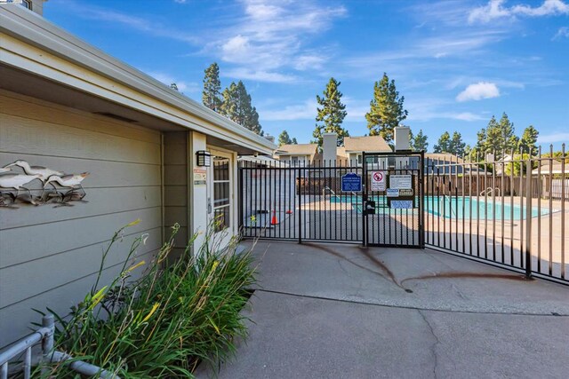 view of gate with a patio and a community pool