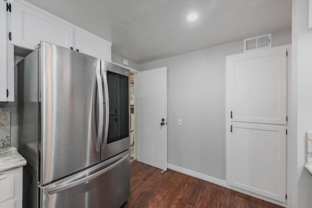 kitchen with white cabinetry, stainless steel refrigerator, dark wood-type flooring, and light stone counters