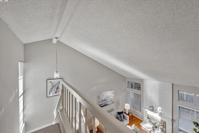 staircase featuring lofted ceiling with beams, a textured ceiling, and hardwood / wood-style flooring