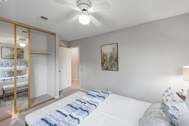 carpeted bedroom with ceiling fan, a textured ceiling, and a closet