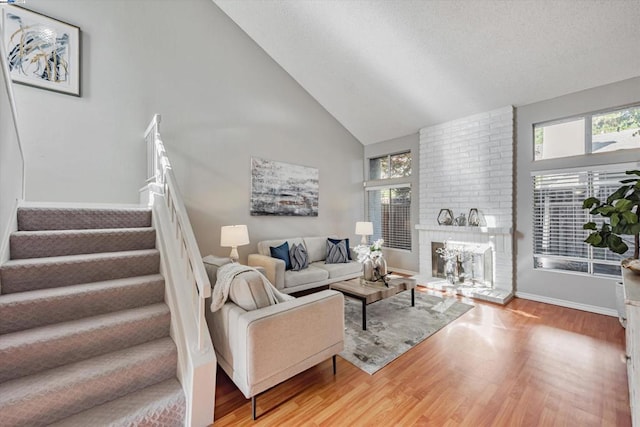 living room with a brick fireplace, hardwood / wood-style flooring, and high vaulted ceiling