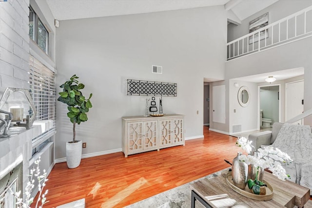 living room with hardwood / wood-style flooring, beam ceiling, and high vaulted ceiling