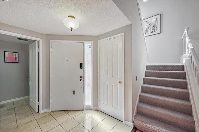 entrance foyer featuring light tile patterned floors and a textured ceiling