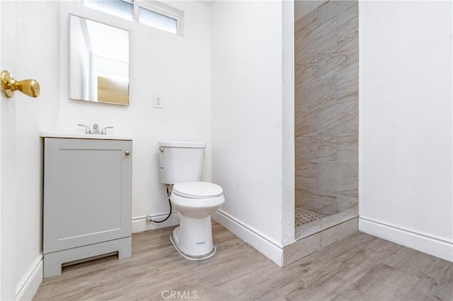 bathroom featuring tiled shower, wood-type flooring, vanity, and toilet