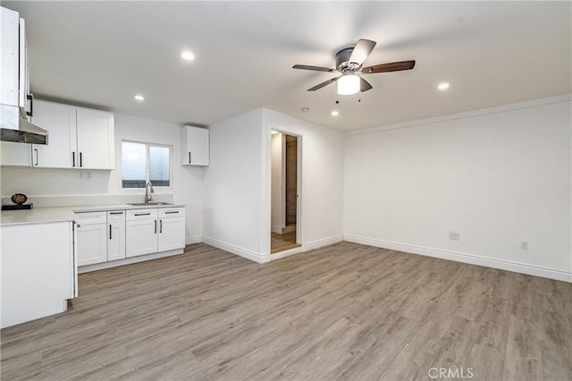 kitchen with white cabinets, light hardwood / wood-style flooring, ceiling fan, and sink